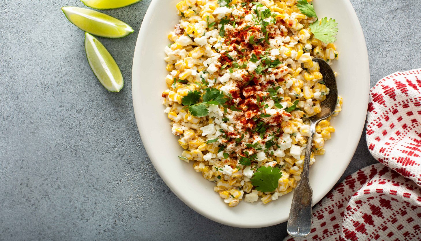 A colorful plate of corn topped with lime and cilantro, inspired by a Mexican street corn popcorn seasoning recipe.