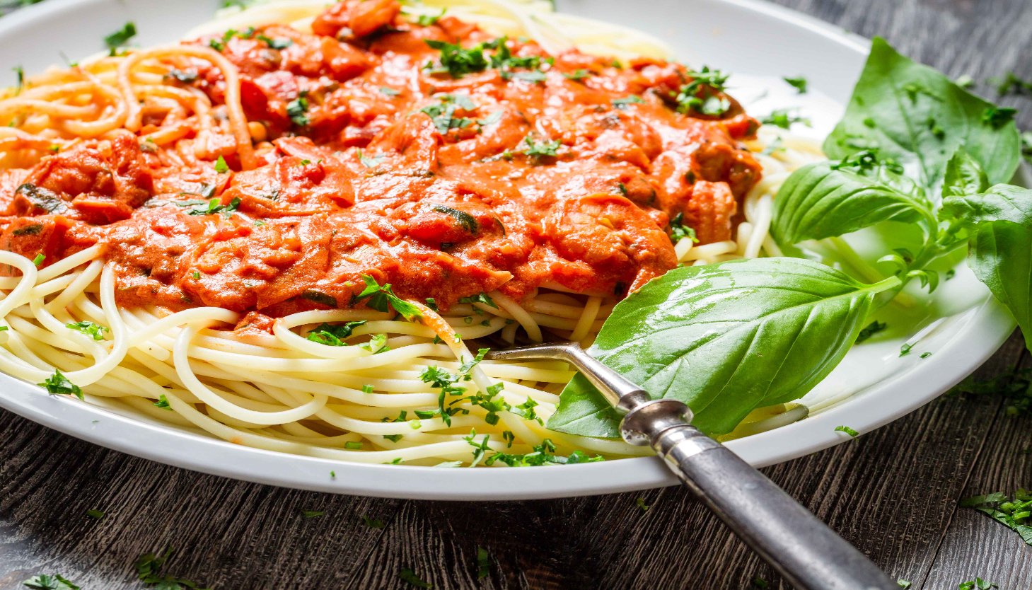 A bowl of spaghetti featuring a luscious tomato sauce and basil, highlighting a delicious meat-free Mediterranean meal.